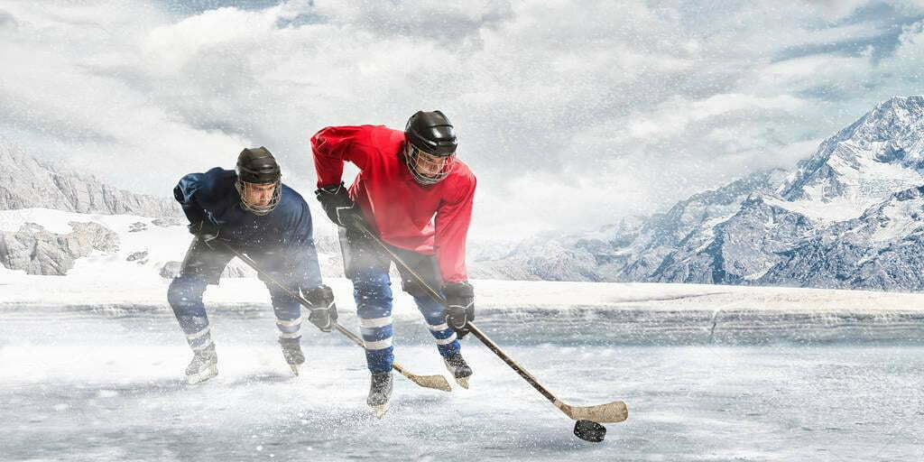 Hockey players skating on an outdoor rink with mountains behind them